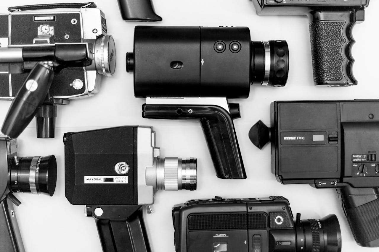 Flat lay of assorted vintage video cameras in black and white photography.